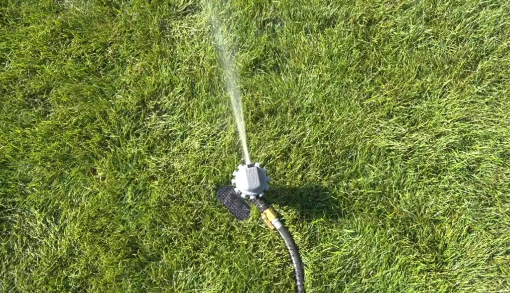 Sprinkler watering a lush green lawn maintained by Waco lawn services