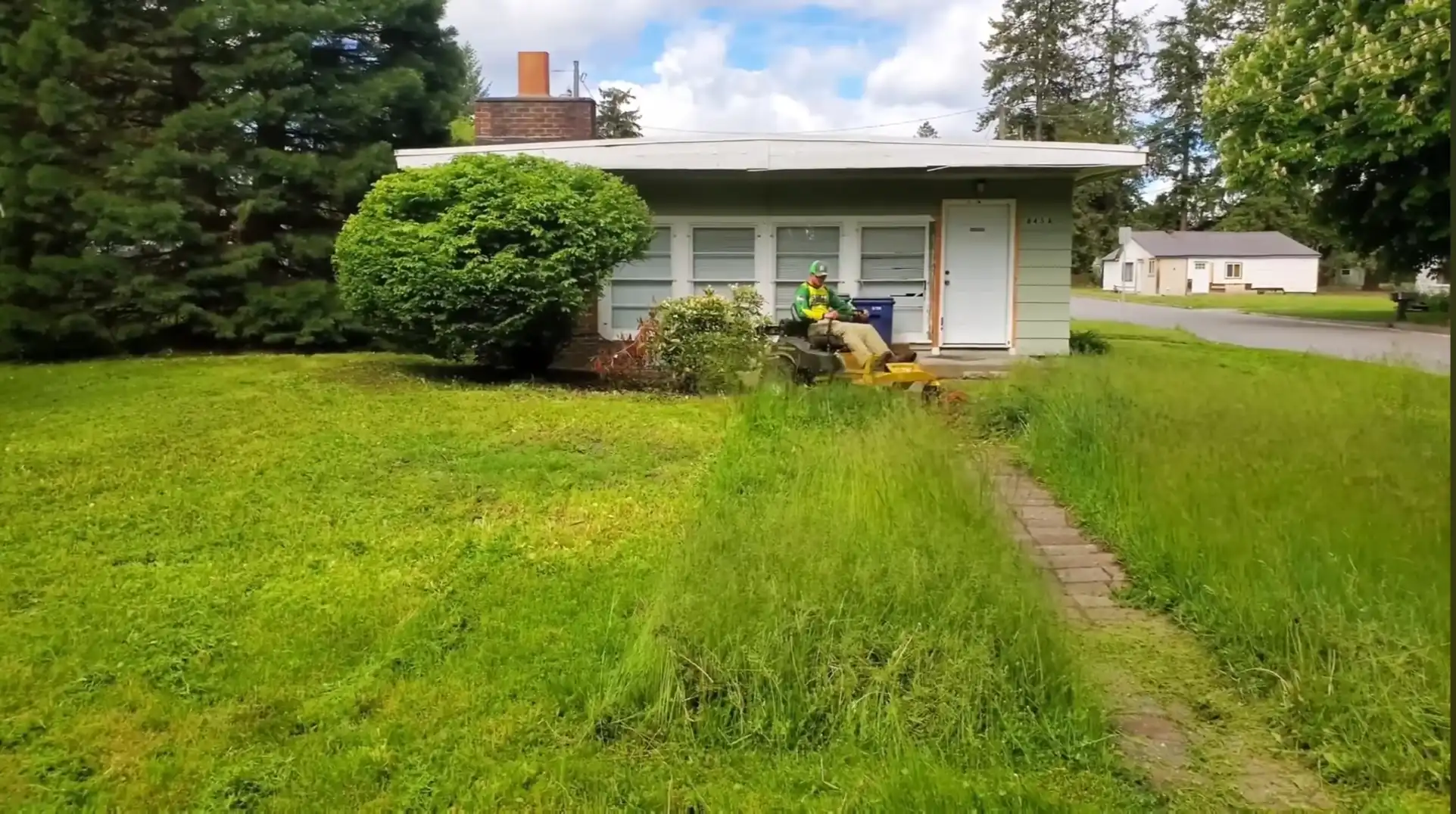Professional Waco lawn services mowing an overgrown front yard with a ride-on mower.